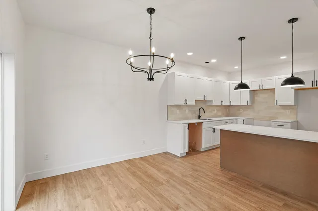 a open kitchen with a sink dishwasher a refrigerator and white cabinets with wooden floor