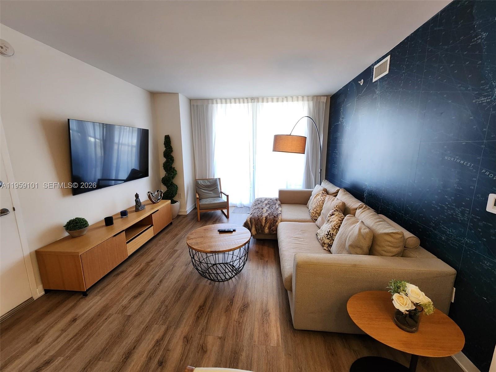 2602 East Hallandale Beach Boulevard, Unit R805 Hallandale Beach, FL 33009 - Photo 3 of 34 a living room with furniture and a flat screen tv