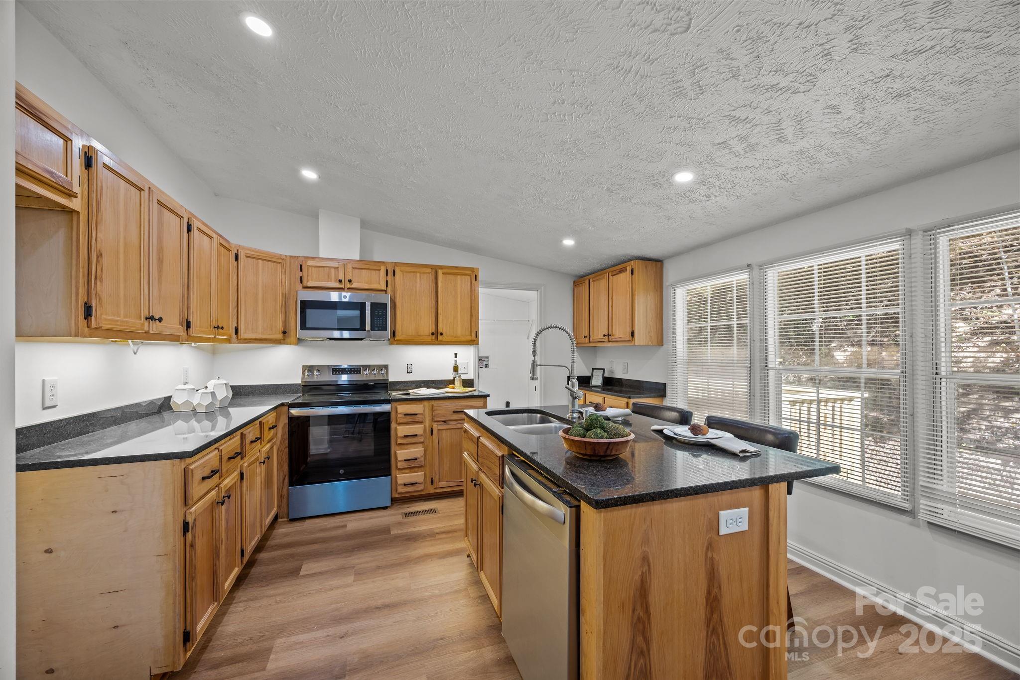 86 Tuts Terrace Sylva, NC 28779 - Photo 12 of 48 a kitchen with stainless steel appliances granite countertop a stove top oven a sink dishwasher a refrigerator and white cabinets with wooden floor