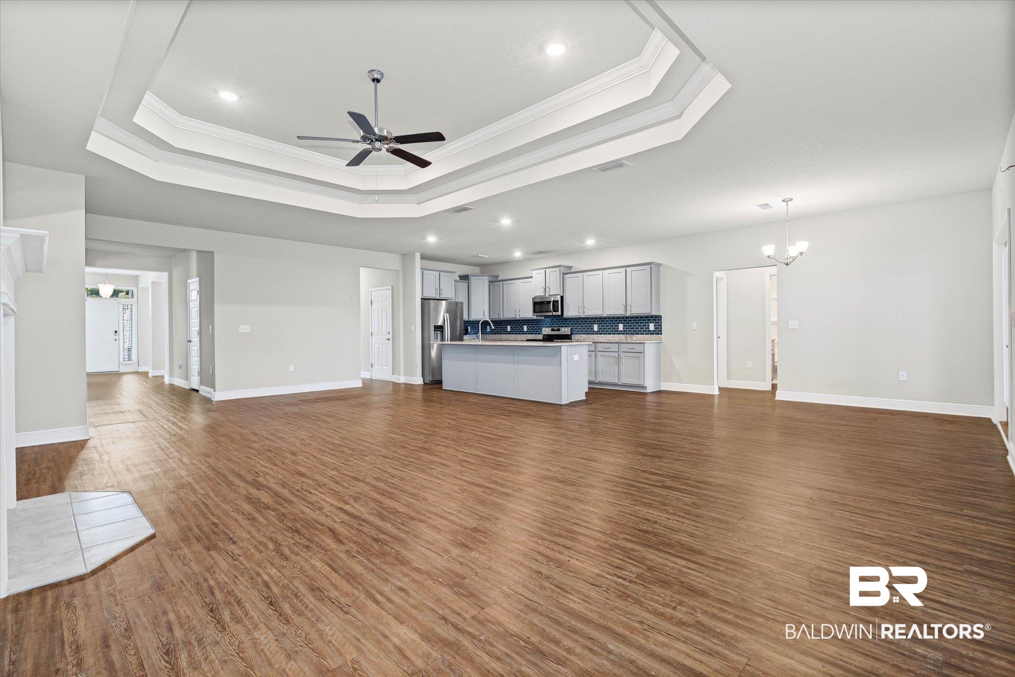 10207 Dunleith Loop Daphne, AL 36526 - Photo 4 of 23 Unfurnished living room featuring a raised ceiling, ornamental molding, dark wood-type flooring, ceiling fan, and a chandelier