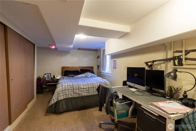 a bedroom with a bed and a computer on a desk next to a window