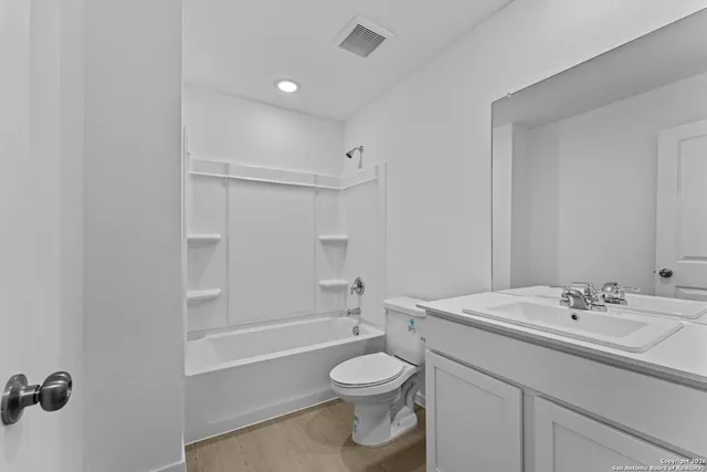 a bathroom with a toilet a sink a mirror a bathtub and vanity