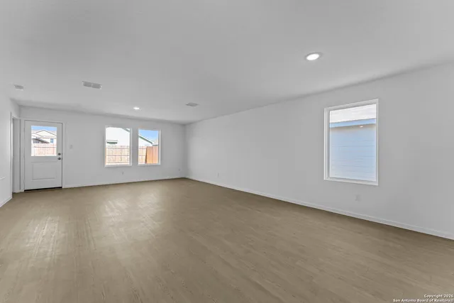 a view of an empty room with a window and wooden floor