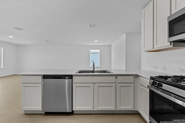 a kitchen with granite countertop a sink cabinets and stainless steel appliances