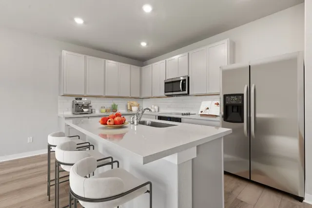 a kitchen with a sink a stove a refrigerator and white cabinets