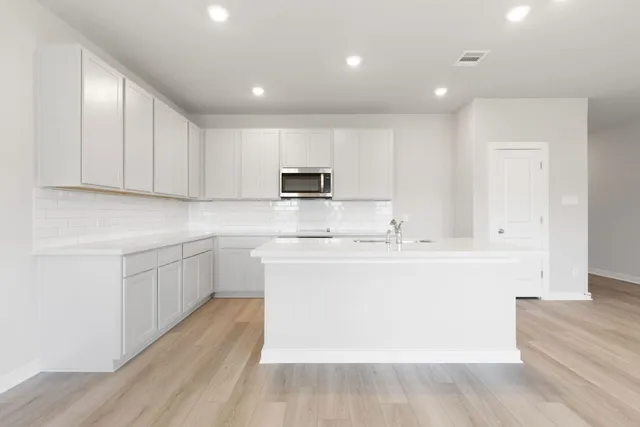 a kitchen with kitchen island sink stove and cabinets