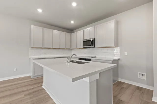 a kitchen with a sink a microwave a stove and cabinets