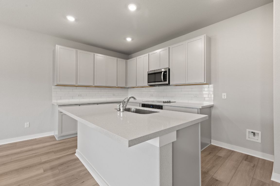 13617 Gray Landing Drive Elgin, TX 78621 - Photo 6 of 29 a kitchen with a sink a microwave a stove and cabinets