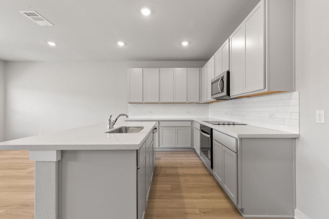 13617 Gray Landing Drive Elgin, TX 78621 - Photo 7 of 29 a kitchen with stainless steel appliances granite countertop a sink stove and cabinets