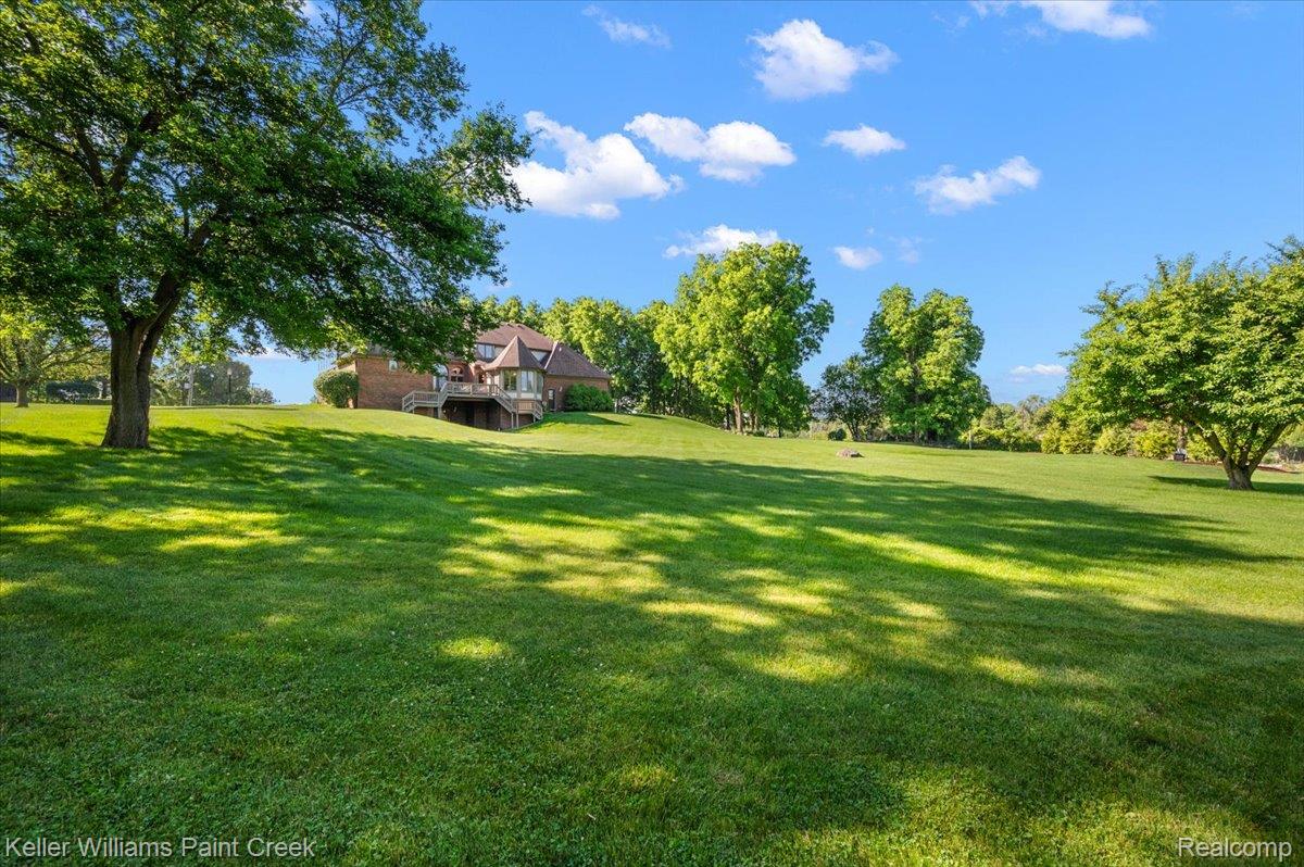 69069 Campground Road Romeo, MI 48065 - Photo 12 of 78 Expansive green lawn with mature trees and a brick residence featuring a multi-level deck