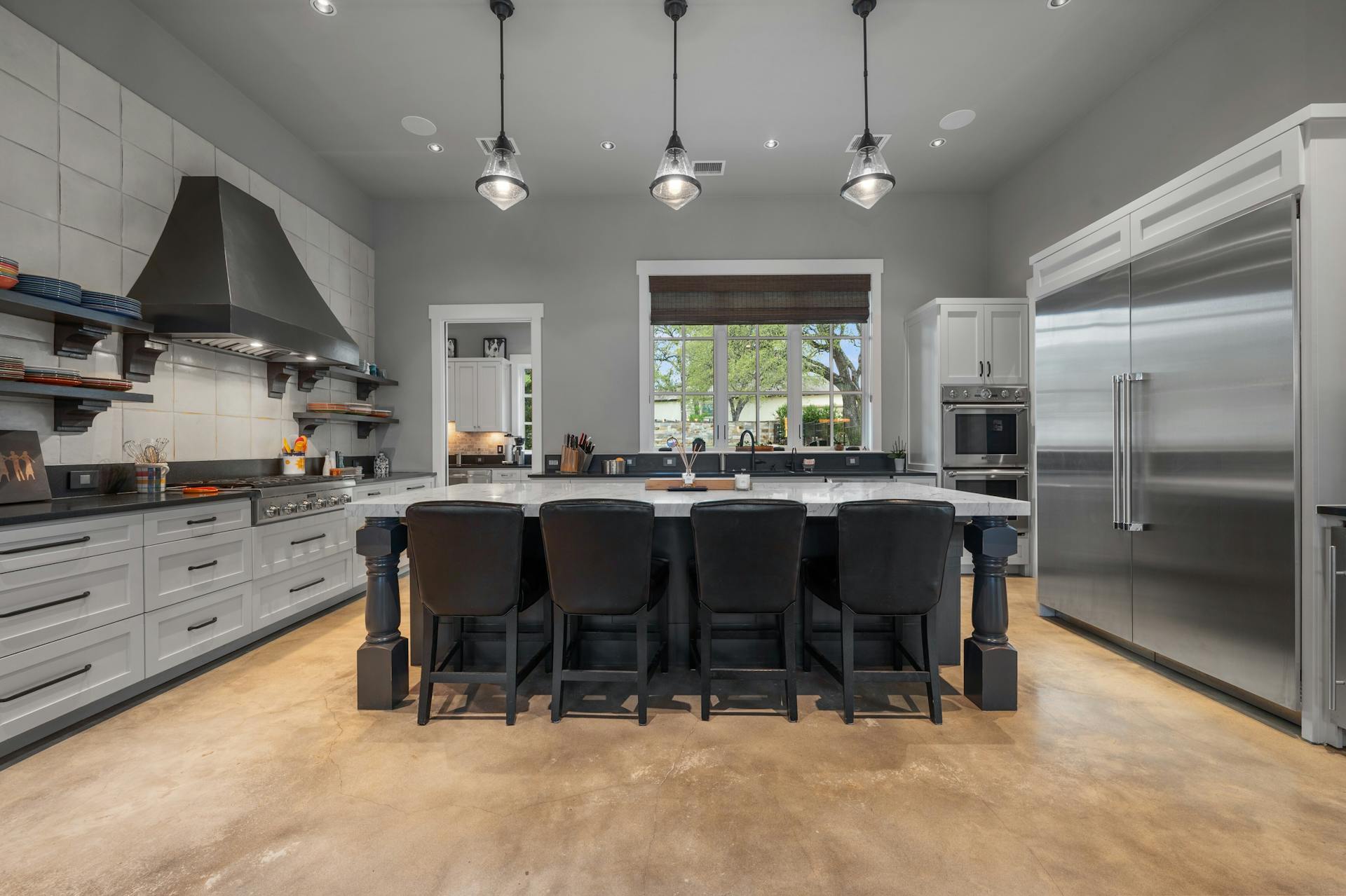 1330 Ranchers Club Lane Driftwood, TX 78619 - Photo 12 of 40 Kitchen featuring open shelves, stainless steel appliances, concrete flooring, ventilation hood, and a large island with sink