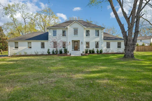 a large white building with a big yard and large trees