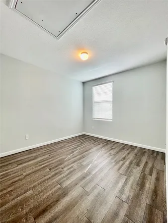 a view of an empty room with window and wooden floor