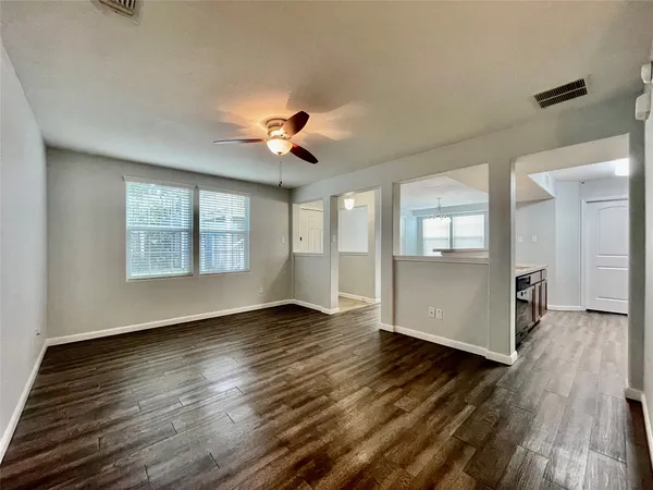 an empty room with wooden floor and windows