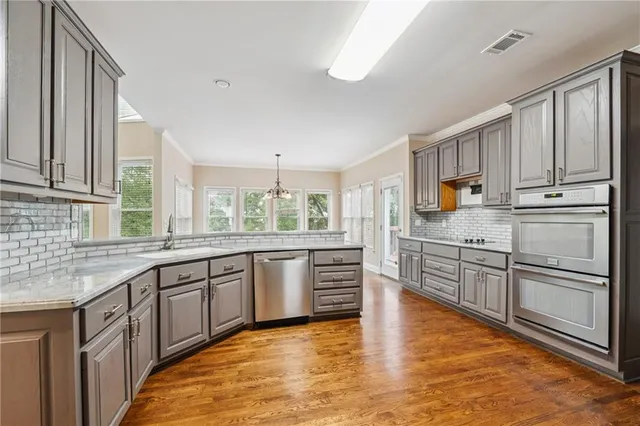 a view of an empty room with wooden floor and windows