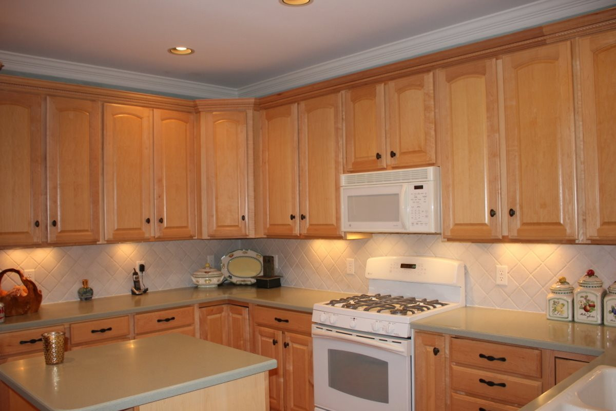 7405 Fontana Ridge Lane Raleigh, NC 27613 - Photo 7 of 25 Aristokraft® Maplewood cabinets, 42” Landen square style - Lots of cabinets with crown molding and designer hardware - Solid surface Corian countertops and ceramic tile backsplash. Kitchen