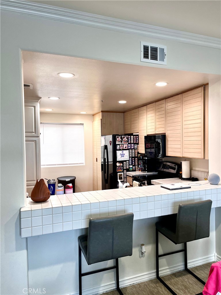 2243 Martin, Unit 409 Irvine, CA 92612 - Photo 4 of 31 a kitchen with a sink a stove a refrigerator and white cabinets with wooden floor