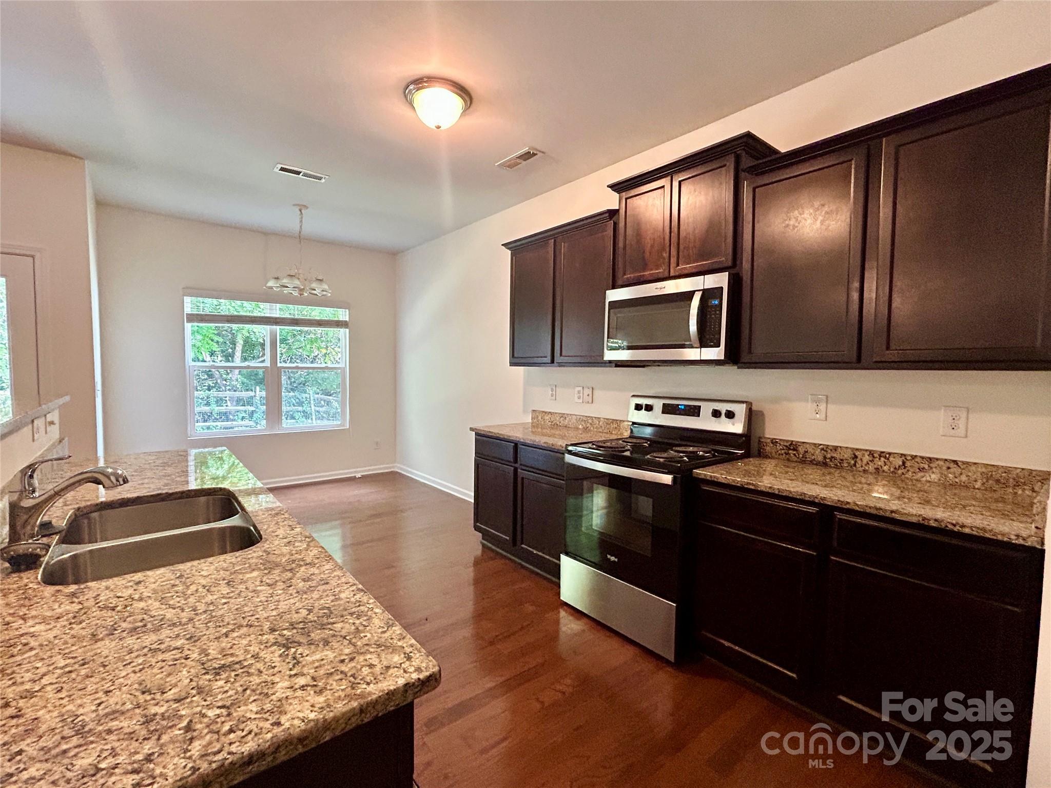 8320 Suttonview Drive Charlotte, NC 28269 - Photo 9 of 34 a kitchen with granite countertop wooden cabinets a stove top oven and granite countertops