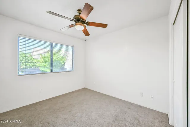 an empty room with a window and a fan