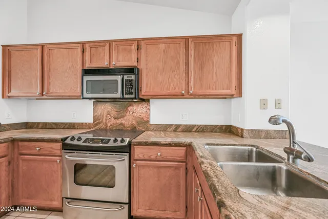a kitchen with granite countertop a sink stove and microwave