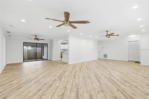 a view of empty room with wooden floor and ceiling fan