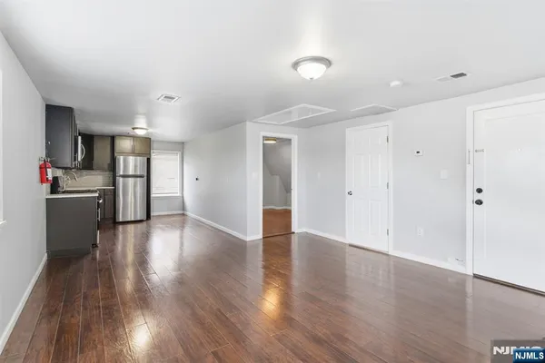 a view of a kitchen with a fridge and wooden floor