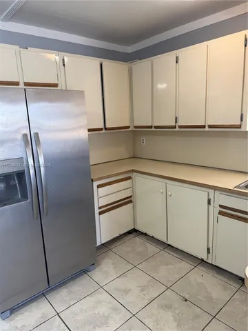 a kitchen with white cabinets and a refrigerator