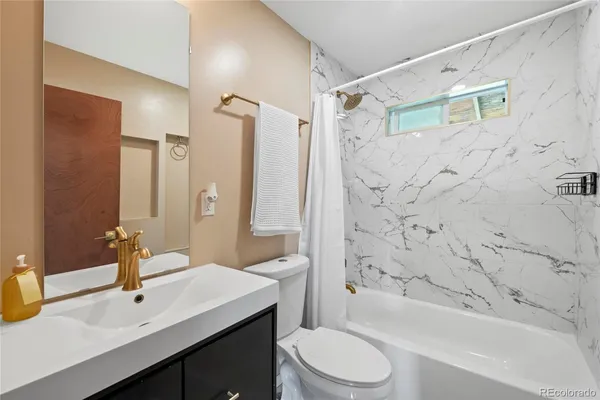 a bathroom with a sink a toilet a mirror a bathtub and shower