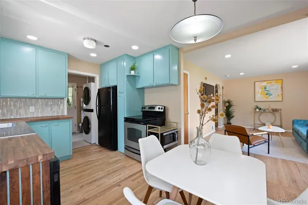 a kitchen with stainless steel appliances granite countertop a refrigerator a microwave oven a dining table and chairs with wooden floor