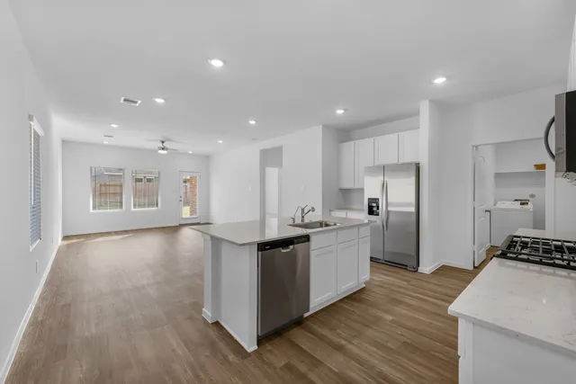 a kitchen with kitchen island a sink dishwasher a refrigerator and a stove with wooden floor