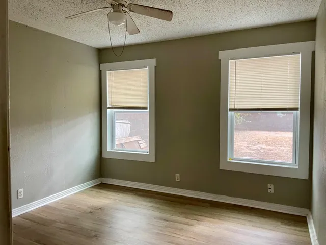 a view of an empty room with a window and wooden floor