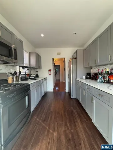 a kitchen with stainless steel appliances granite countertop a refrigerator a stove top oven a sink dishwasher and wooden cabinets with wooden floor