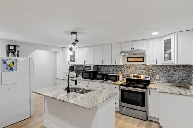 a kitchen with granite countertop a sink stainless steel appliances and cabinets