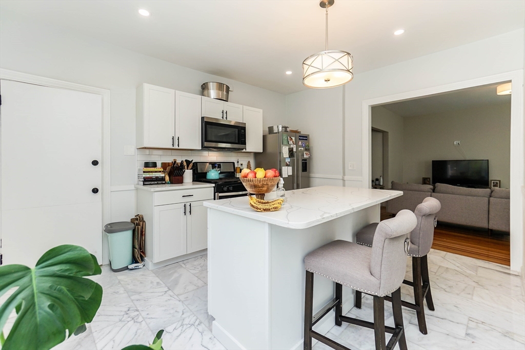 51 Main Street, Unit 2 Somerville, MA 02145 - Photo 2 of 23 a kitchen with stainless steel appliances kitchen island granite countertop a sink and a refrigerator