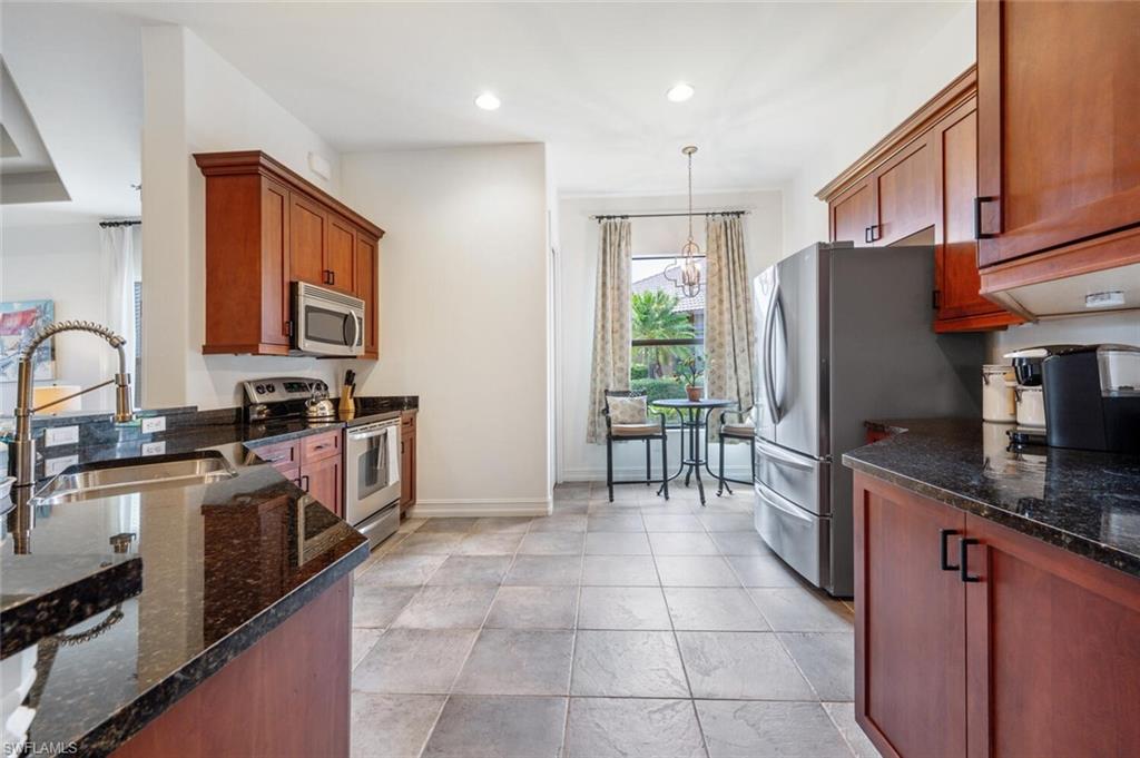 7563 Moorgate Point Way Naples, FL 34113 - Photo 12 of 50 a kitchen with granite countertop a refrigerator stove top oven and sink