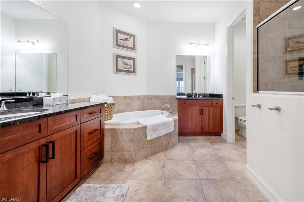 7563 Moorgate Point Way Naples, FL 34113 - Photo 16 of 50 a spacious bathroom with a granite countertop double vanity sink a mirror a bathtub and window