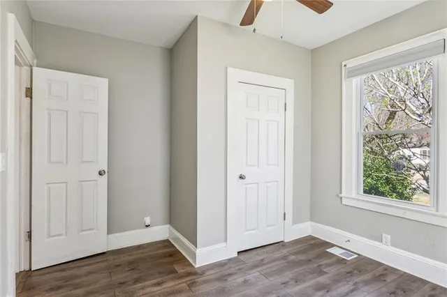 a view of an empty room with wooden floor and a window