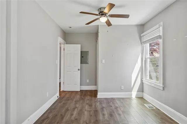 an empty room with wooden floor fan and windows