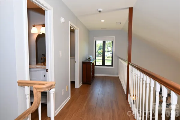 a view of a hallway with wooden floor and a bathroom