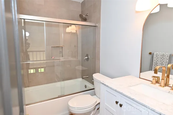 a bathroom with a granite countertop bathtub shower sink vanity and toilet