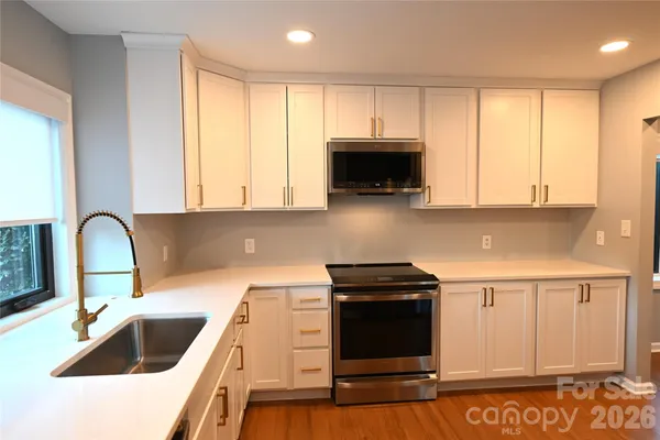 a kitchen with stainless steel appliances a stove a sink a microwave and cabinets