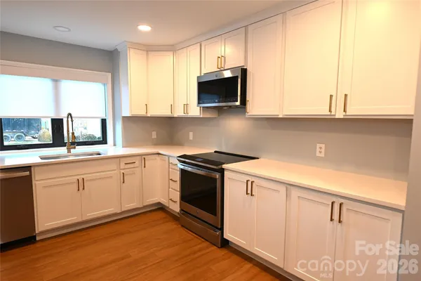 a kitchen with stainless steel appliances granite countertop a stove a sink and a microwave