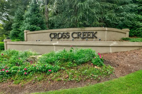 a view of a sign board with flower plants and wooden fence