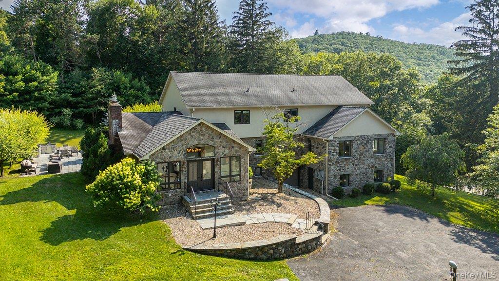 237 Mineral Springs Road Highland Mills, NY 10930 - Photo 2 of 32 Rear view of house with stone siding, a yard, a wooded view, and stucco siding