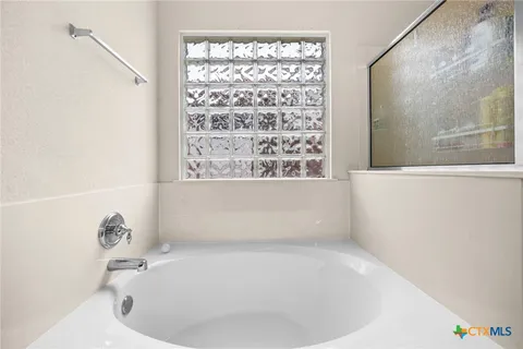 a white bath tub sitting in a bathroom next to a window