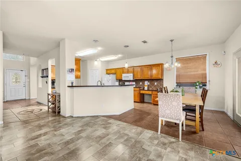 a view of a kitchen with kitchen island stainless steel appliances refrigerator stove dining table and chairs