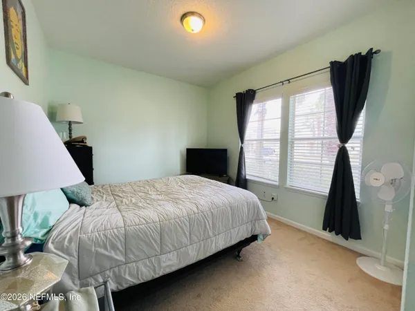 a bedroom with a bed next to a window with chair and table