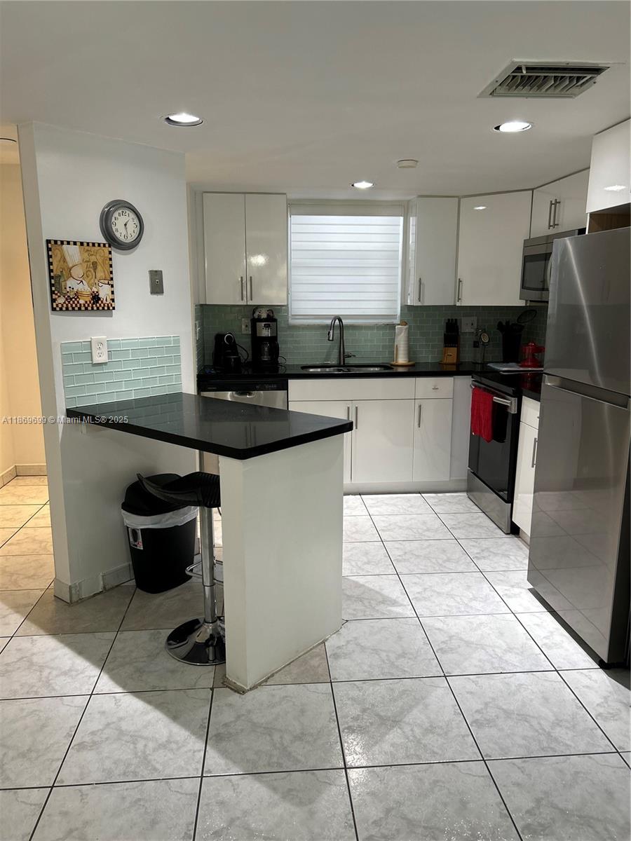 17801 North Bay Road, Unit 203 Sunny Isles Beach, FL 33160 - Photo 4 of 23 a kitchen with stainless steel appliances kitchen island granite countertop a sink and cabinets