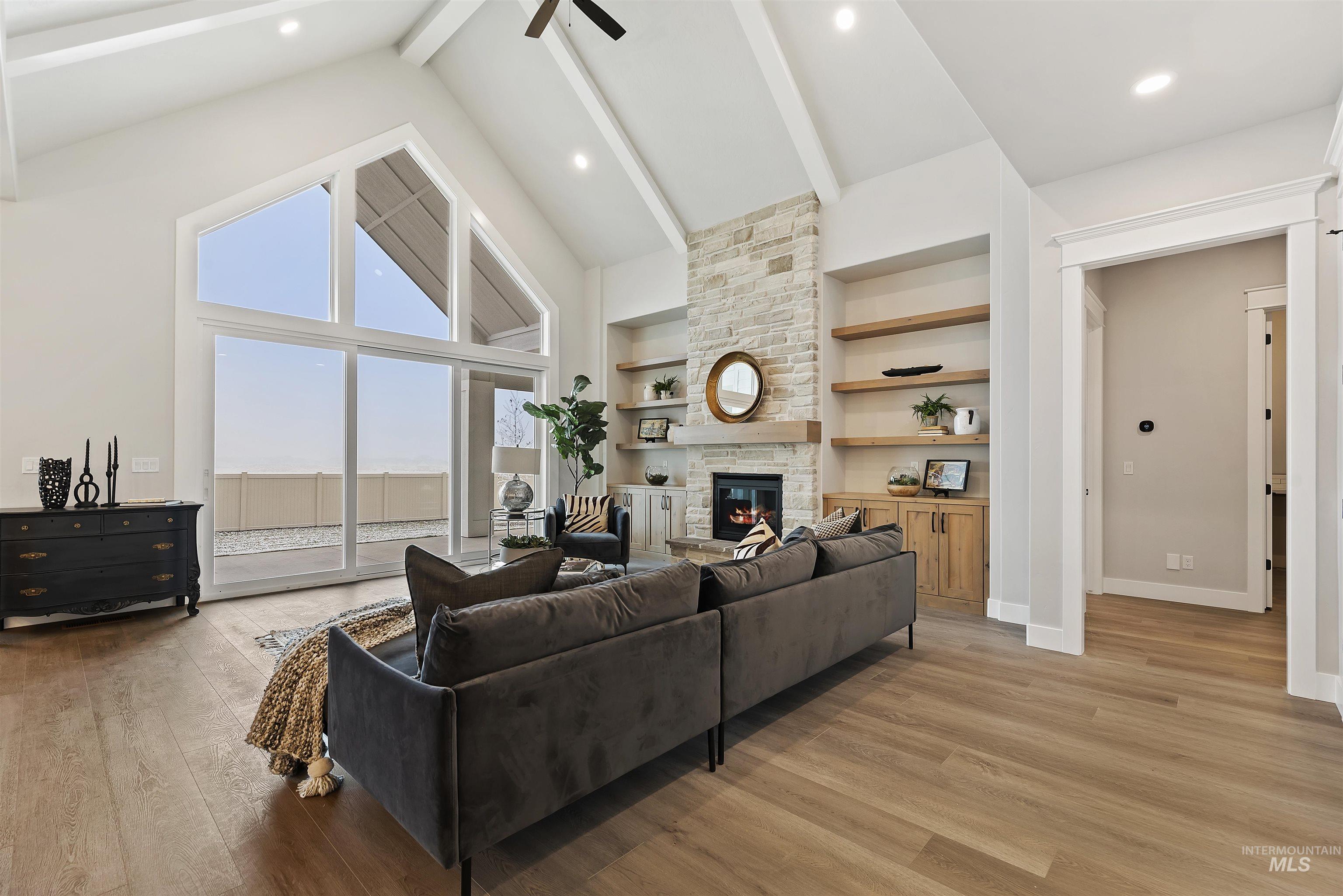 Living area with light wood-style flooring, a stone fireplace, built in features, a ceiling fan, and recessed lighting