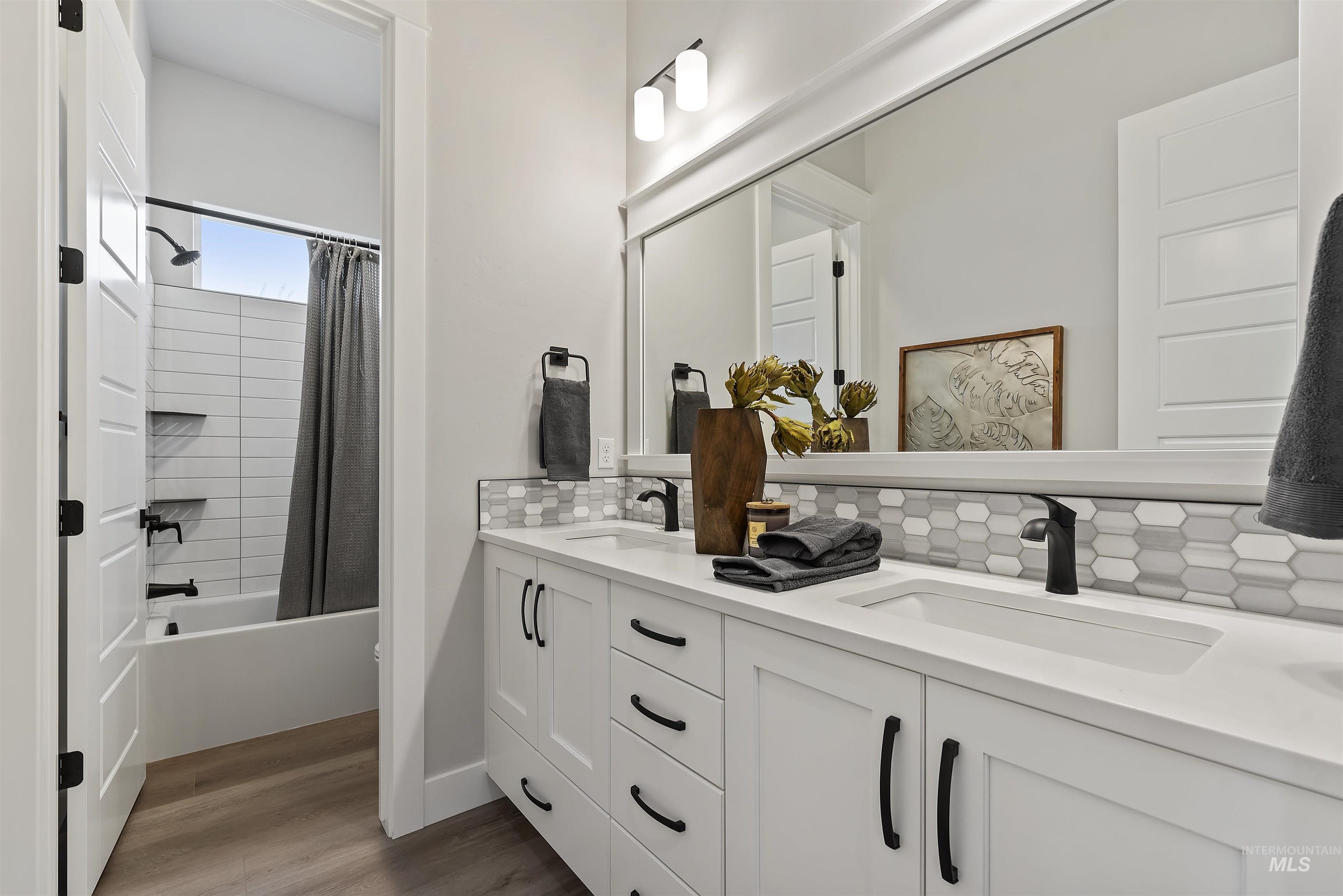 9283 Basin Kid Court Middleton, ID 83644 - Photo 14 of 21 Bathroom with double vanity, shower / bath combo with shower curtain, light wood-type flooring, and decorative backsplash